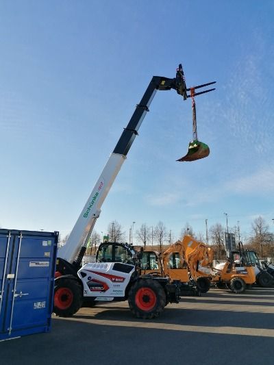 Baugeräte und Baustellenbedarf mieten - Bobcat Teleskopkran transportiert eine Baggerschaufel